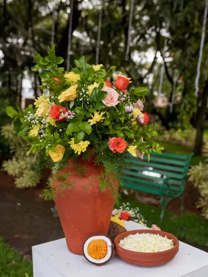 An earthy and beautiful floral arrangement in a terracotta pot, combining roses with local flowers and greens.