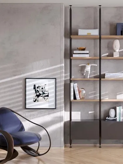 A quiet corner in the office, featuring a minimalist shelving unit and a sculptural armchair. The play of sunlight across the concrete-textured wall adds a dynamic, natural element to the workspace.
