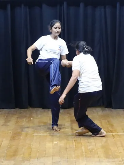 The confidence gained from our training is evident when participants showcase their skills. Here, a woman demonstrates a powerful knee strike defense, a culmination of the practical training received during our women's self-defense program.