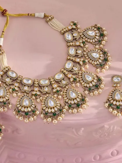 A classic Polki necklace set with green bead drops, a versatile piece that complements many bridal outfits.
