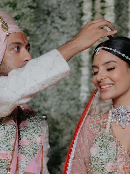 A beautiful, traditional moment. The groom applies the sindoor, and her makeup remains perfectly in place, highlighting her serene expression.