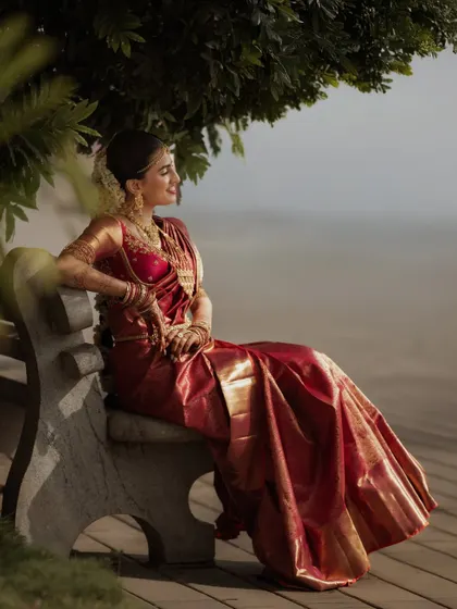 The bride seated on a bench, looking out over the water. This quiet, contemplative portrait captures a moment of peace before the day's festivities.