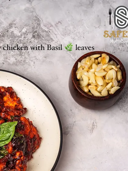 A close-up view of our Crispy Chicken with Basil, showcasing the glossy sauce coating the chicken and the fresh basil leaves, with a side of chopped garlic to highlight the key ingredients.