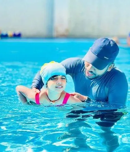 A coach provides physical support to help a student practice her floating and kicking technique. This hands-on assistance is crucial for beginners to feel the correct body position.