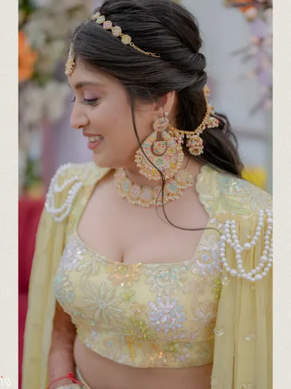 A close-up shot of the bride's smiling face and her unique pearl-draped cape blouse.