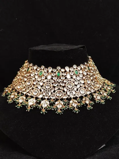 A classic and elegant Kundan choker with floral motifs and green bead drops. This timeless design is a favorite in our rental collection.