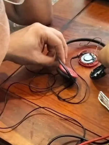 A close up of a mentor's hands carefully repairing a set of headphones. This image highlights the precision and patience required for delicate electronic repairs.