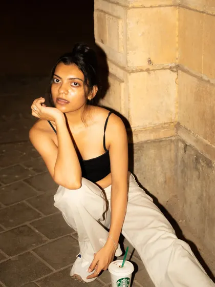 A casual, crouched pose on the pavement. This adds an urban, street-style authenticity to the night shoot.