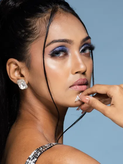 A profile view of the model, showing off the dramatic blue eyeshadow and flawless skin. Different angles are key to a comprehensive beauty portfolio.