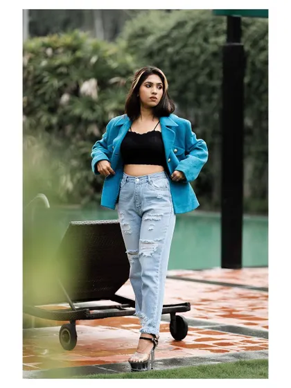 An outdoor fashion shot with a cool, urban feel. The model's pose is confident and her outfit is modern and stylish.