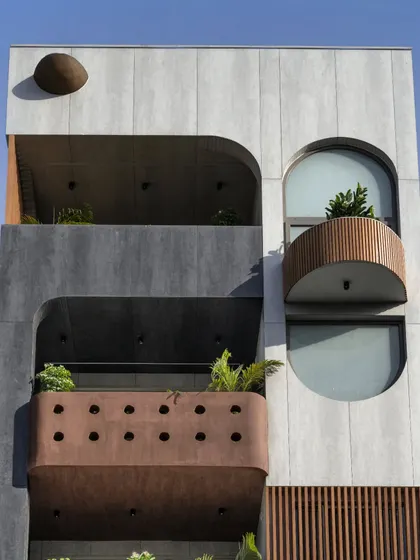 The façade of the Slender House is simple yet interesting, using corten steel texture paint, wooden battens, and grey tiles. The soft curves of the balconies and window openings are a recurring motif, extending from the exterior into the interior spaces.