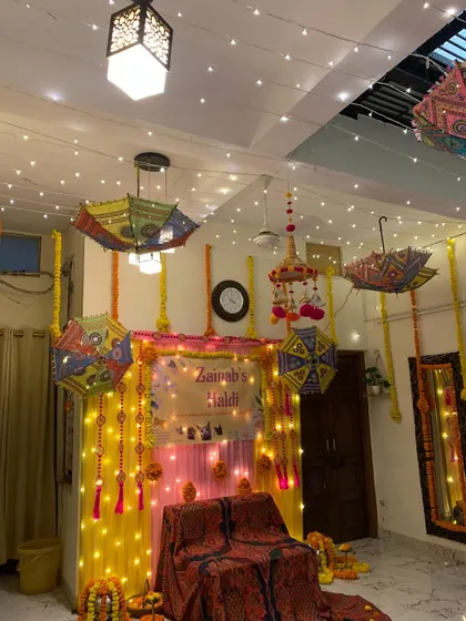 A wider view of the home Haldi decor, showing how fairy lights on the ceiling and hanging umbrellas can create a magical, festive atmosphere throughout the room.