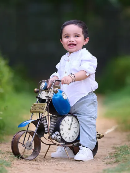 Ready to ride into his first birthday celebration. This happy toddler poses with a classic toy motorcycle, a popular prop that always brings out the smiles.