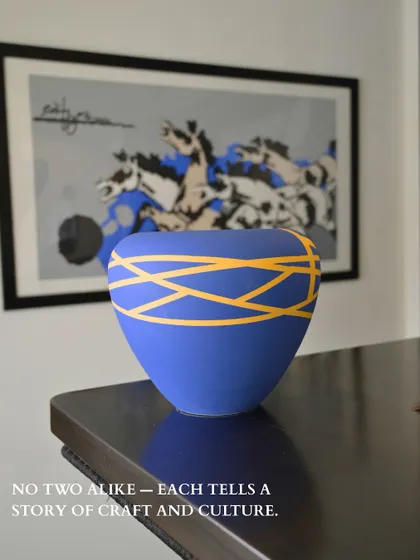This vibrant blue vase with its energetic yellow lines is a celebration of color and form. Placed against a piece of modern art, it shows how our curated vases can interact with and enhance other artistic elements in your home.