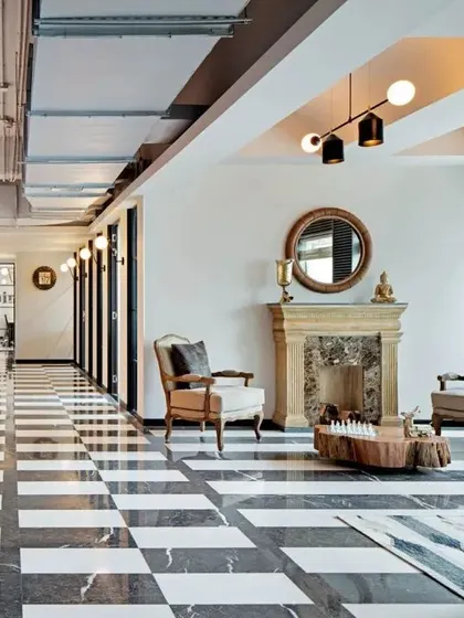 This lounge area in a contemporary workspace features a classic chequered floor and a vintage-style fireplace, creating a sophisticated yet comfortable breakout zone. It's a space designed for informal meetings or a quiet break from the desk.