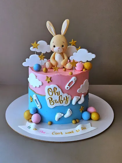 A sweet bunny-themed baby shower cake. This "He or She, Can't wait to See" cake is perfect for a gender reveal, with a cute fondant bunny and pastel colors.