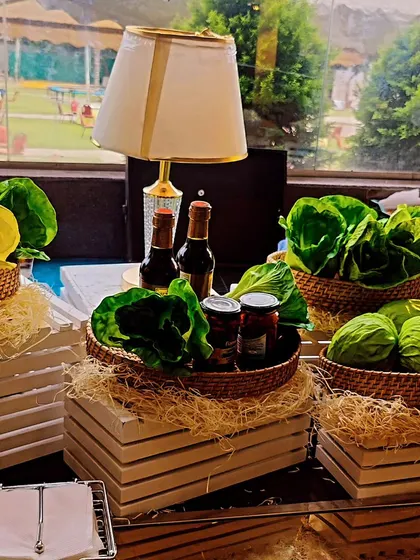 A fresh and green setup for our salad bar at an outdoor event. We use whole heads of lettuce and fresh vegetables as part of the decor, emphasizing the farm-to-table quality of our ingredients.