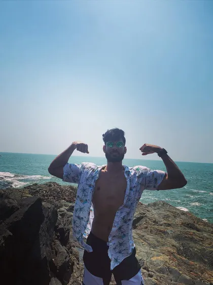 Posing on the rocks by the ocean, with an open shirt showing a lean and defined core.