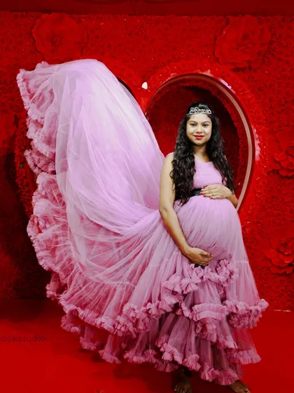 A dramatic shot of a lavender maternity gown with its long, ruffled trail fanned out, creating a beautiful and artistic portrait.