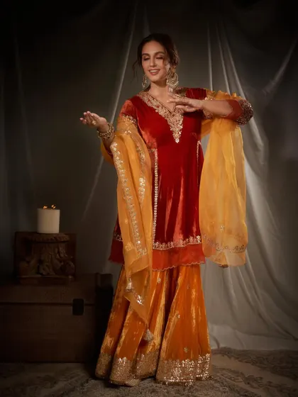 A joyful, candid moment that shows how comfortable and vibrant this festive outfit is. The combination of red and orange velvet is both traditional and eye-catching.