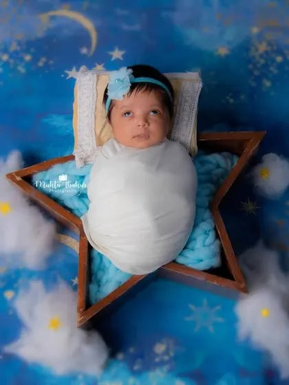 A star is born! This little one looks so peaceful nestled in a star-shaped prop, surrounded by fluffy clouds and a magical night sky.