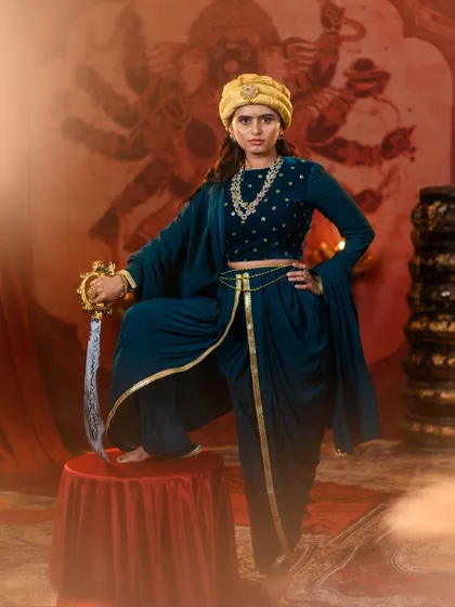 Embodying strength and grace, this is our recreation of the 'Manikarnika' look. The teal dhoti-style outfit with a turban is a powerful and unique choice for a themed event or photoshoot.