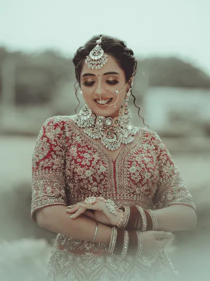 A gentle and shy smile from the bride. This close-up portrait beautifully captures her intricate jewelry, from the nath to the choker, and her delicate expression.