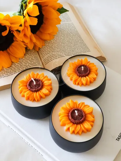 A trio of my Sunflower tin jar candles, looking bright and cheerful next to some real sunflowers.