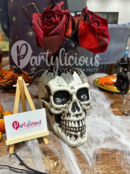For a touch of gothic romance at your Halloween party, this skull vase holding deep red roses is the perfect centerpiece. It's a great example of how I blend spooky themes with elegant, stylish details.