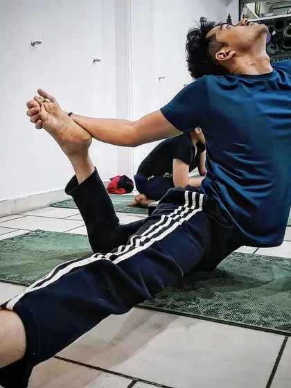 A student practices a variation of Eka Pada Rajakapotasana, focusing on hip opening and spinal extension.
