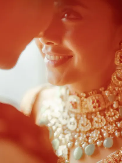 A close-up filled with warmth and affection, capturing the bride's joyful smile and the stunning detail of her bridal jewelry.