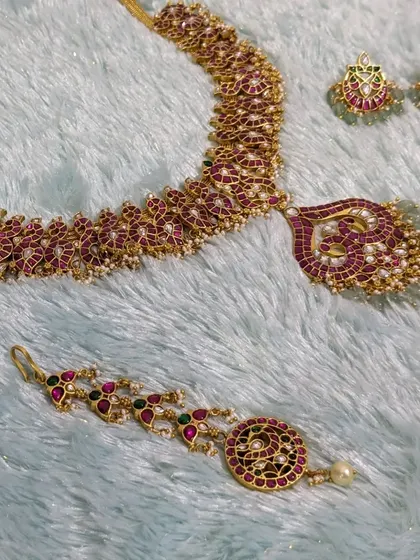 The full pink Jadau set laid out, showing the necklace, earrings, and maang tikka.