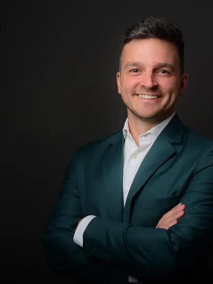 A classic headshot with a genuine smile. A dark background ensures the focus remains on the subject, making it a versatile choice for any professional use.