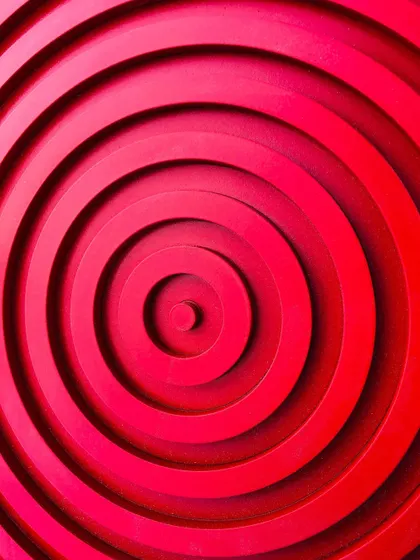 A macro close-up of the center of the red abstract art, highlighting the precision of the layered rings.