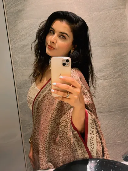 A mirror selfie from the same client, showing how the dupatta, made from her mother's saree, drapes beautifully with her fusion outfit and the elegant pearl choker.