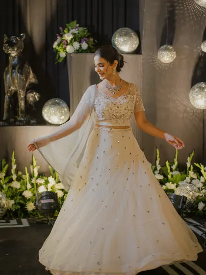 A joyful pose in the same white lehenga, capturing the fun and festive spirit of a wedding celebration.