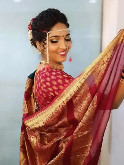 A beautiful shot of the bride holding her saree's 'padar', showcasing the rich fabric and the way her makeup glows in the light.