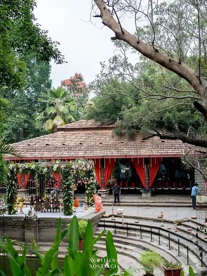 A wide shot of the Pond Pavilion, decorated with red drapes, ready for a vibrant and traditional wedding ceremony.