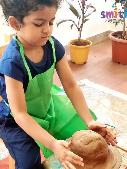 A child experiences the magic of pottery, shaping clay on a wheel to form a diya. This tactile, sensory activity is a highlight of our Diwali preparations.