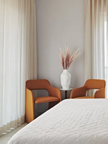 We added a pair of vibrant orange chairs to this bedroom in the Maximum City Duplex to create a bold color accent. They provide a comfortable seating area while adding a strong design element to the room.