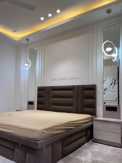 A full view of the minimalist bedroom, showing the bed with its elegant upholstered headboard, flanked by tall mirrors and modern pendant lights.