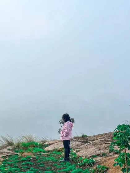 A contemplative moment for a hiker in the misty hills of Bananthimari.
