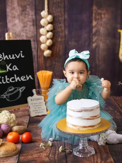 Welcome to Bhuvi's Kitchen. This little chef is already tasting the cake. The personalized chalkboard adds a sweet, custom touch to the session.