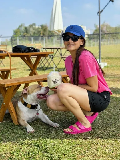 An owner enjoying a branded coconut from our cafe while her dog relaxes in the shade of the picnic table.