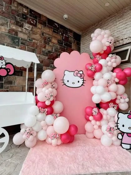 An adorable Hello Kitty themed photo corner. This setup includes a cute candy cart, character cutouts, and a pink and white balloon arrangement, creating the perfect spot for memorable photos.