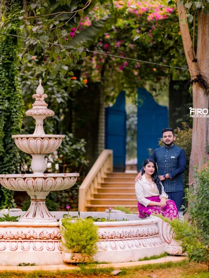 A regal portrait by a classic fountain. The couple's traditional attire, with rich colors and textures, adds a touch of royal elegance to this beautiful garden scene.