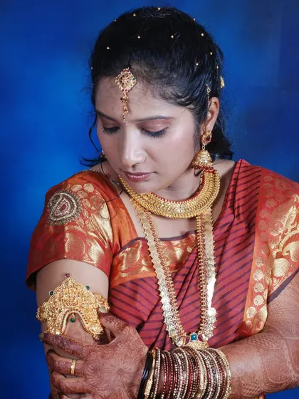 A bridal portrait showcasing traditional South Indian gold jewelry, including a Vanki (armlet) and Kasu Malai.