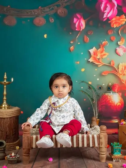 A festive and vibrant setup for this little one. The rich colors, traditional lamps, and floral backdrop create a beautiful, celebratory atmosphere for a milestone shoot.