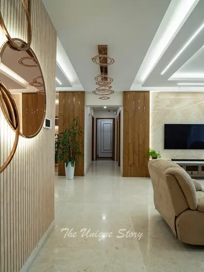 This long shot of the living area shows the seamless flow from the entryway to the main seating area. The fluted wall panel with a backlit sculptural mirror serves as an artistic focal point, guiding the eye through the space.
