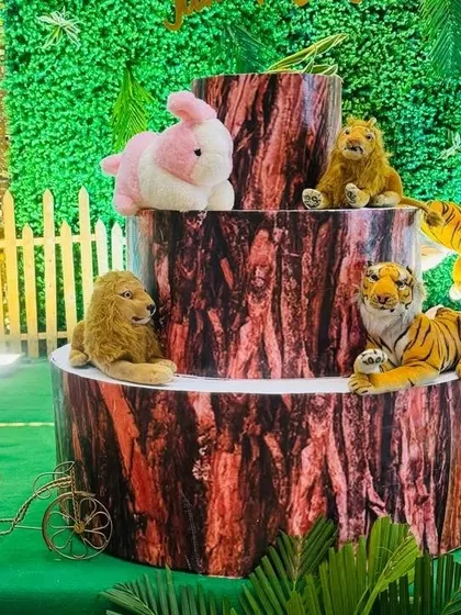 A detailed view of the three-tiered tree stump cake stand, decorated with plush animal toys to match the jungle theme.